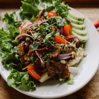 Grilled Thai beef salad with fresh greens, tomato and red onion